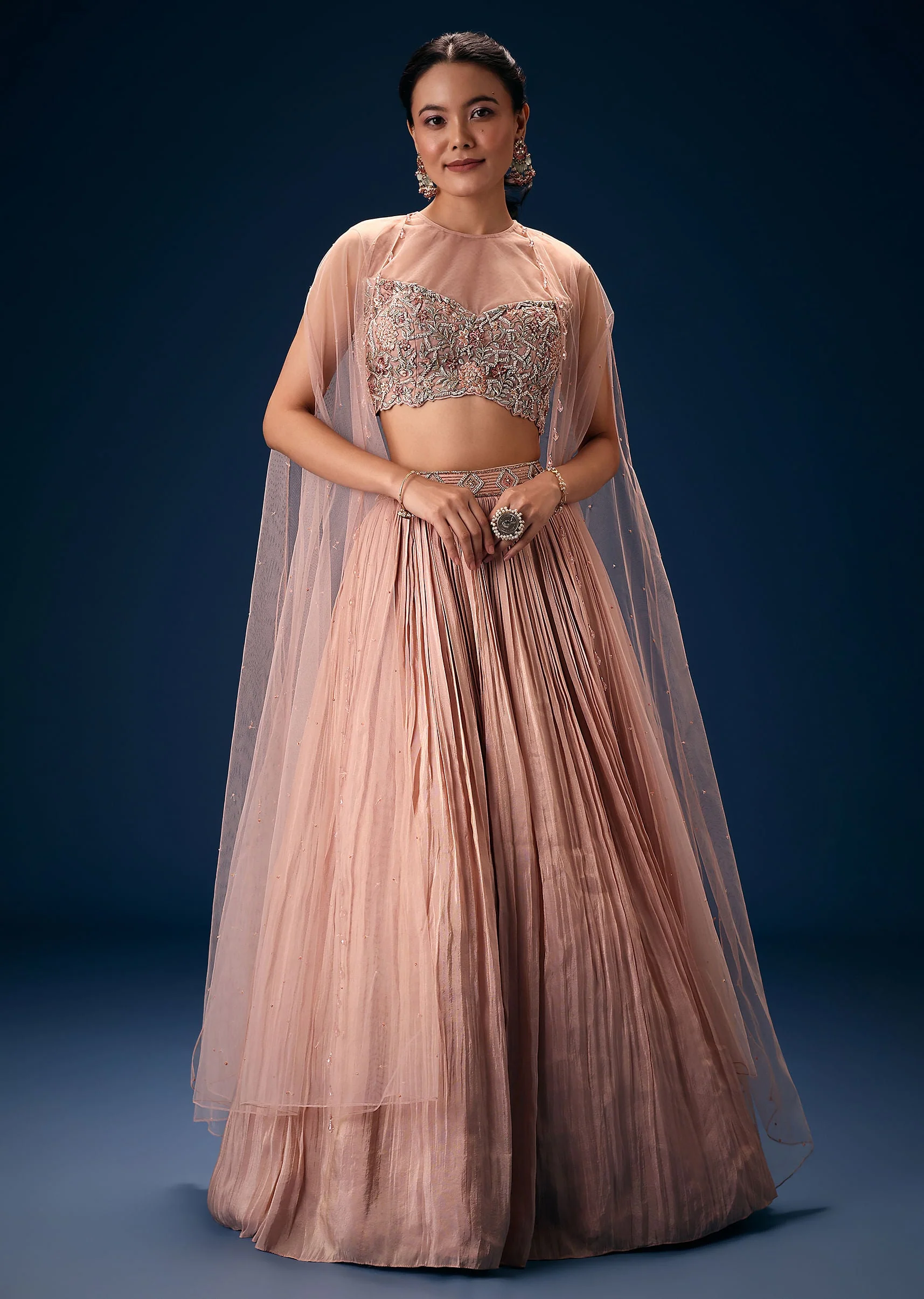 11043-peach-ruched-lehenga-with-embroidered-blouse-and-net-cape-3.webp Peach Ruched Lehenga With Embroidered Blouse and Net Cape